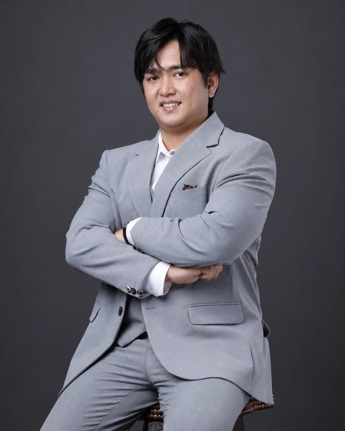 Edison smiling with his arms crossed in the same grey studio suit